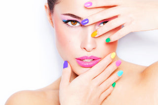 Woman with colorful nail polish covering her face on a white background
