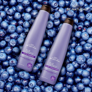 Two bottles of Blueberry shampoo and conditioner surrounded by blueberries with 'Be Natural' branding.
