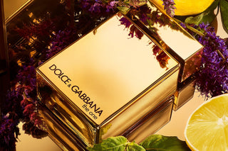 Dolce & Gabbana perfume bottle with flowers and lemon slices on a reflective surface