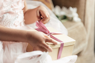 Person holding a gift box with a pink ribbon in a soft-focus setting